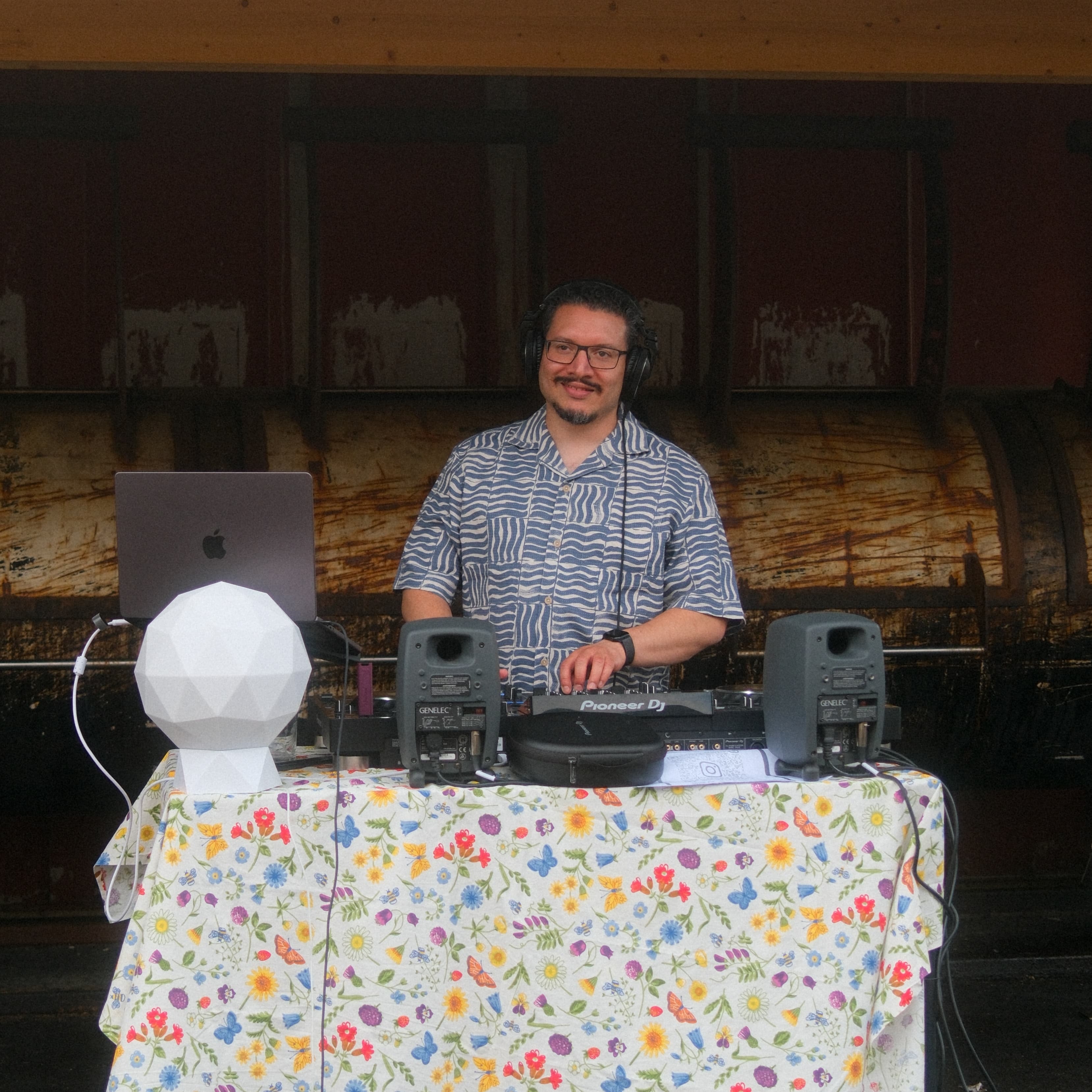 DJ Freddy spelar bakom ett kompakt DJ-bord under ett utomhusevent